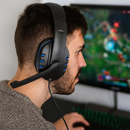 Casque gaming noir avec accents bleus, microphone flexible, porté par un homme face à un écran d'ordinateur flou.