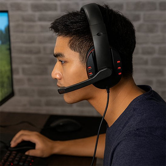 Casque audio gaming noir avec micro ajustable, détails rouges sur l'oreillette, porté par un joueur concentré de profil droit.