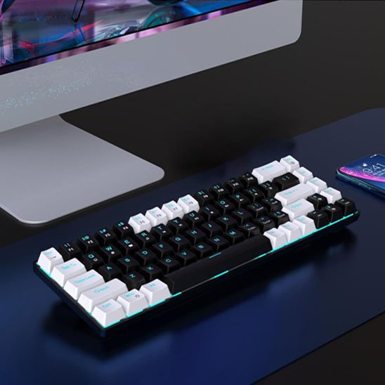 Clavier ergonomique noir et blanc avec touches rétroéclairées bleu, design compact et moderne sur bureau sombre au pied d’un .