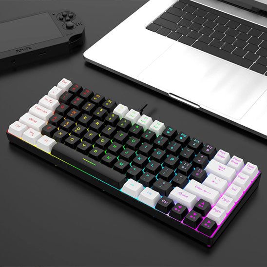 Clavier ergonomique compact noir avec touches blanches et éclairage RGB multicolore sous les touches, posé à côté d'un.