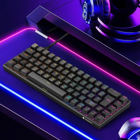 Clavier mécanique compact noir avec éclairage RGB sous les touches, posé sur un bureau lumineux avec des bandes LED rose et.