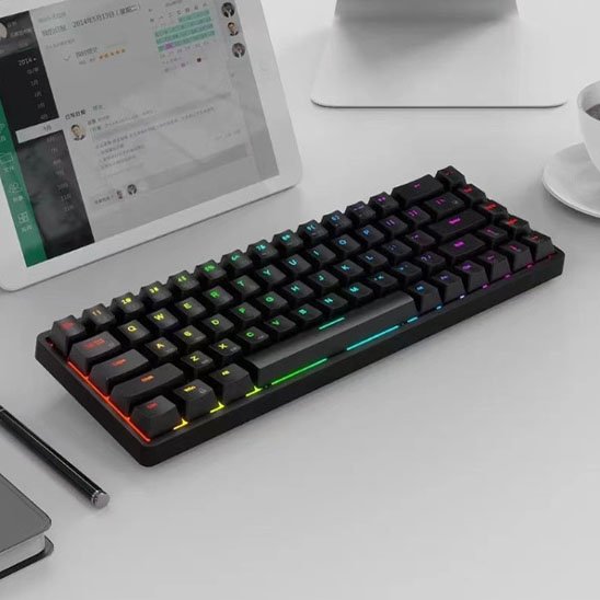Clavier compact mécanique noir avec rétroéclairage RGB multicolore sur bureau blanc, clavier sans pavé numérique.
