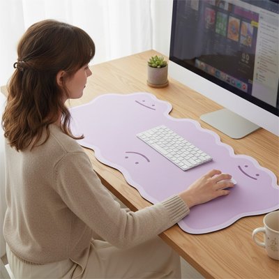 Tapis de souris XXL lilas en forme ondulée avec repose-poignets intégrés, clavier blanc et plante verte sur bureau en bois.